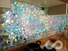 a kitchen counter topped with lots of colorful glass tile backsplashes on the wall