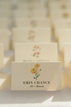 small business cards with flowers on them are sitting on a white tablecloth covered table