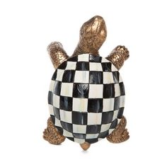 a ceramic turtle sitting on top of a white and black checkered surface