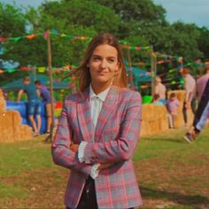 a woman standing in front of hay bales with her arms crossed and looking at the camera