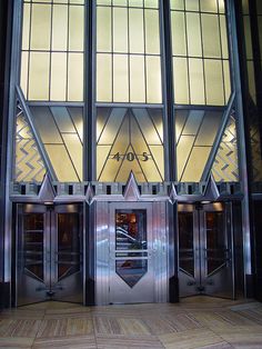 the entrance to an elevator is lit up by stained glass panels and decorative doors with geometric designs on them