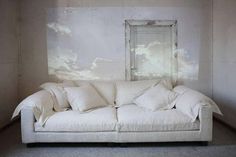 a white couch sitting next to a wall with clouds painted on the wall behind it