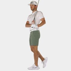 a man holding a golf club while standing in front of a white background