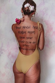 the back of a woman's body with words written on it and flowers in her hair