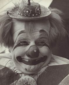 an old photo of a clown wearing a hat and holding a doughnut in his hand