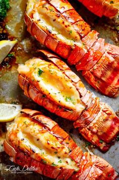 cooked lobsters on a baking sheet with lemon wedges and parsley