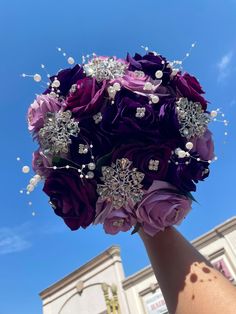 a bridal bouquet in front of a building with blue sky and clouds behind it