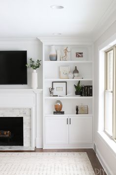 a living room filled with furniture and a flat screen tv mounted on a white wall