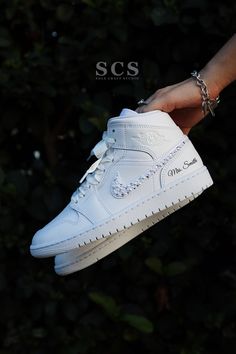 a hand holding a white shoe with chains on it