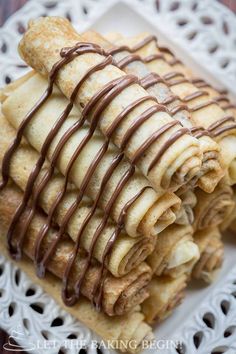 a white plate topped with crepes covered in chocolate