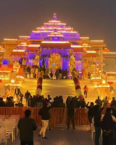 a group of people standing in front of a building with lights on it at night