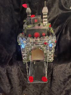 a castle made out of glass with red roses on the front and sides, sitting on a black background