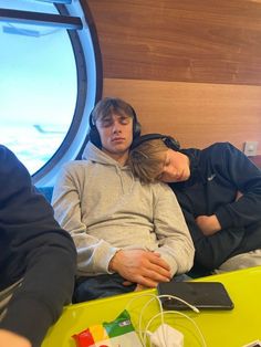 two people are sleeping on a bed with headphones