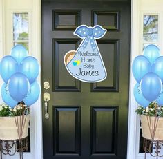 blue balloons in front of a black door with welcome home sign and name on it