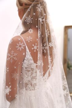 a woman wearing a wedding veil with snowflakes on it