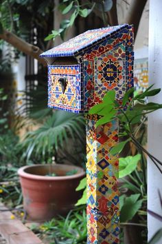 a colorful mailbox sitting on the side of a building next to a potted plant