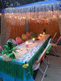 a long table with candles on it in front of a wall and some lights hanging from the ceiling