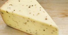 a wedge of cheese sitting on top of a wooden table