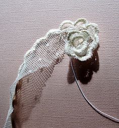 a piece of white lace with a flower on it sitting on top of a pink surface