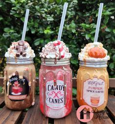 three mason jars with candy canes and whipped cream in them sitting on a wooden table