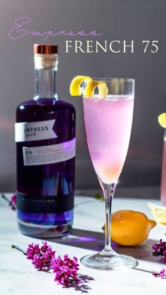 a glass filled with pink liquid next to a bottle of lavender lemonade and some sliced lemons