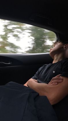 a man sleeping in the back seat of a car with his head on his arm