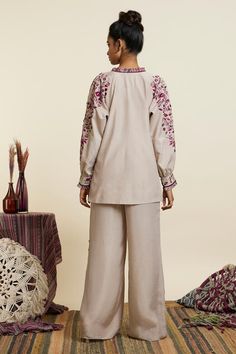 Grey crepe top with contrast flower vase, floral motifs, thread, sequin embroidery and layered loop tassel details. Paired with embroidered flared pants.
Components: 2
Pattern: Embroidered
Type Of Work: Thread, Sequin Work
Neckline: Frill Neck
Sleeve Type: Dolman Sleeves
Fabric: Crepe
Color: Grey
Other Details: 
Side slits
Embellished tassels
Embroidered sleeve cuffs
Top Closure: Front tasselled tie-up
Occasion: Work - Aza Fashions Cuffed Top, Crepe Top, Sequin Embroidery, Top And Pants Set, Sequins Embroidery, Flared Pants, Floral Motifs, Pant Set, Embroidered Top