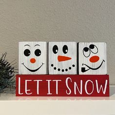 three snowman blocks sitting on top of a white shelf next to a potted plant