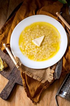 a white bowl filled with soup and topped with a piece of cheese on top of it