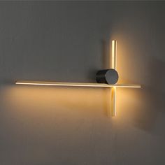 a light that is on the wall next to a white wall with a black object in it