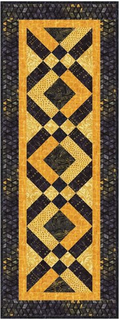 a black and yellow quilt with an orange border on it's side, in the middle