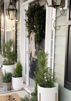 two white planters are on the front porch with wreaths and numbers in them