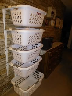 three white laundry baskets stacked on top of each other in front of a brick wall