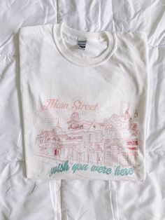 Main Street Greetings Graphic Tee Say hello to the Greetings Collection! A collection of tees so nostalgic looking that you'll think you found it in the back of your local vintage shop. We made sure to include every detail of each land that only a true fan of the parks would pick out. It's buttery soft, the perfect gift for a friend, and can be styled both oversized with biker shorts or more fitted with your favorite pair of sweats. What you will get: A soft, lightweight shirt with the right amo Senior Merch, Theme Park Shirts, Thrift Inspo, Sorority Merch, Graphic Tee Vintage, Main Street Usa, Shirt Design Inspiration, Graphic Tees Vintage, Graphic Tee Design