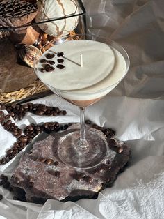 a drink in a martini glass sitting on top of a table next to bread and coffee beans