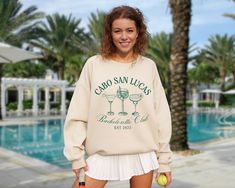 a woman standing next to a pool holding a tennis racquet and an apple