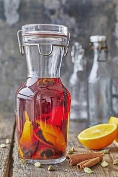 a glass bottle filled with liquid sitting on top of a wooden table next to an orange slice