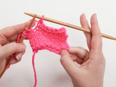 two hands holding knitting needles and crochet hook