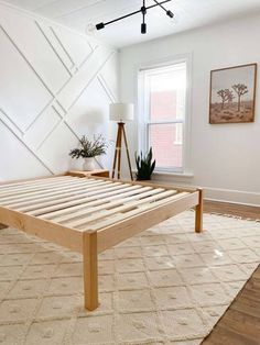 a bed frame in the middle of a room with a rug on the floor next to it