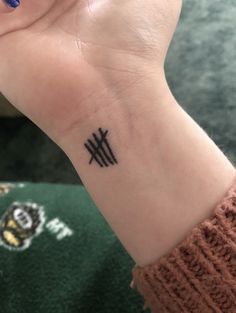 a woman's wrist with a small black tattoo on her left hand and an arrow in the middle