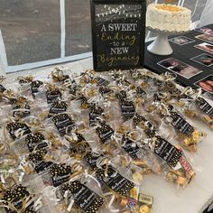 a table topped with lots of small candies and desserts next to a sign