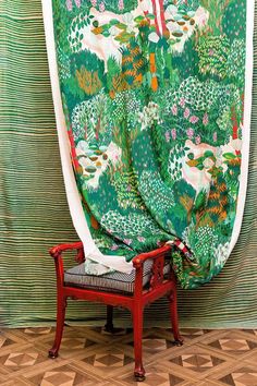 a chair sitting in front of a wall covered with a green and white fabric draped over it