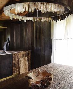 a wooden table and chair in a room with wood paneling on the walls, an old fashioned light fixture hanging from the ceiling