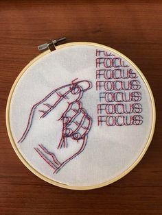 a hand embroidered on a wooden surface with the words focus focus focus focus