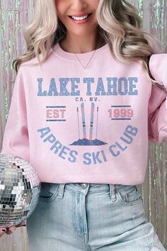 a woman with blonde hair wearing a pink lake tahoe sweatshirt and jeans holding a disco ball