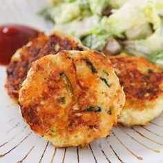 two crab cakes on a plate next to some vegetables