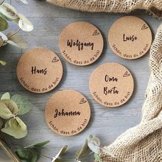 four personalized cork coasters with names on them next to flowers and burlocks