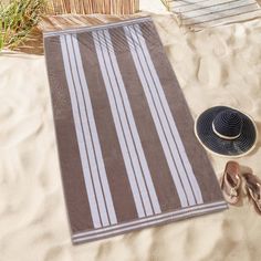 a towel, hat and flip flops on the beach