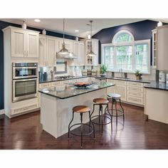 a large kitchen with an island and three stools