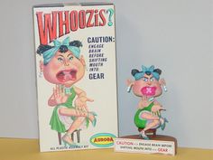 a box and figurine sitting next to each other on a table with a sign that says whoozies?